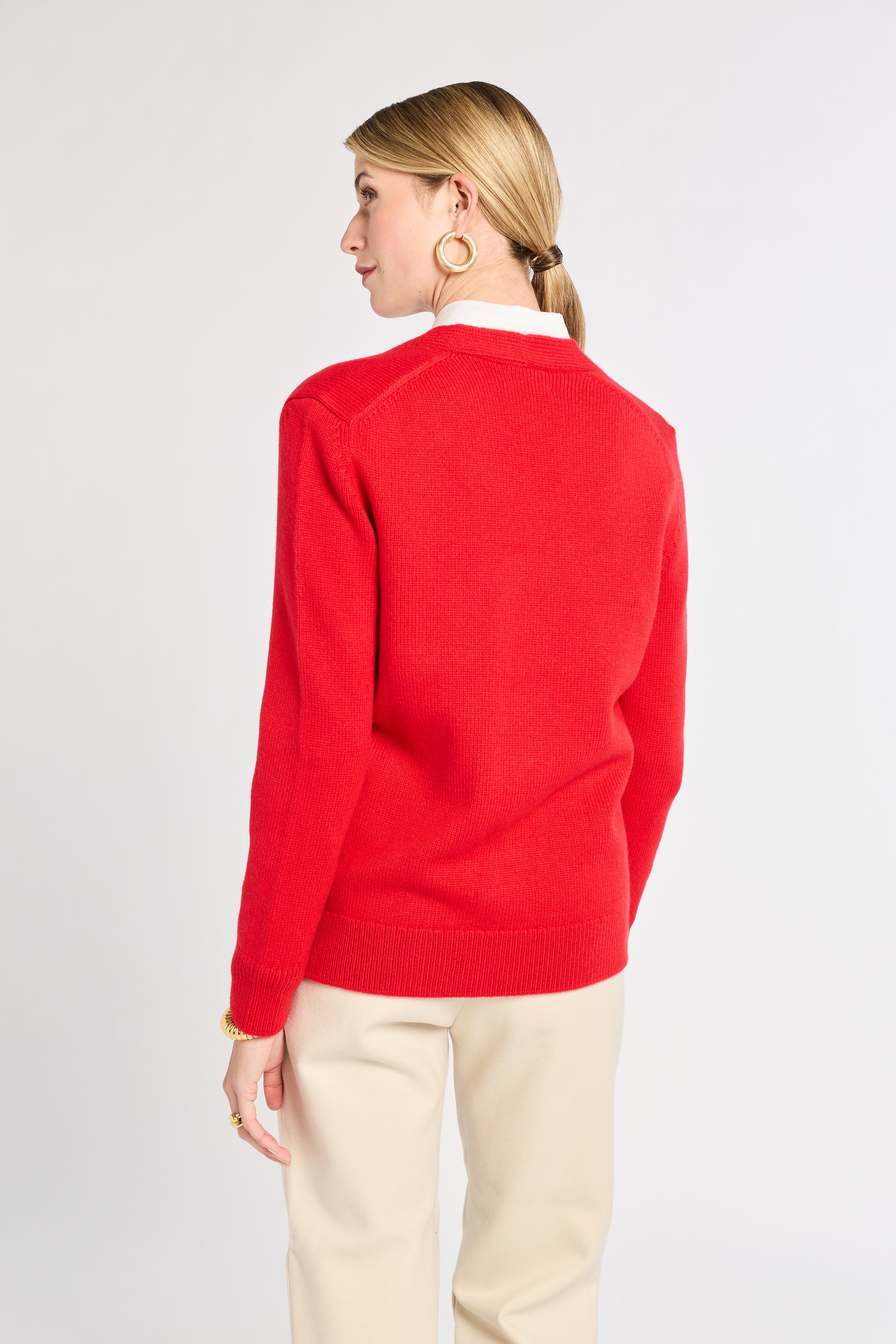 Person wearing a red sweater and beige pants on a white background