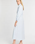 Woman wearing a light blue striped dress on a white background