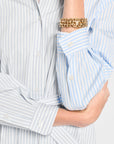 Close-up of a person wearing a light blue and white striped shirt with rolled-up sleeves, focusing on the collar and cuffs.
