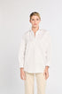 Woman wearing a white blouse and beige pants on a light gray background
