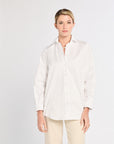 Woman wearing a white blouse and beige pants on a light gray background