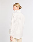 Woman wearing a white blouse against a plain background