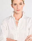 Woman wearing a white shirt with a pearl necklace and watch on a plain background