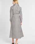 Woman wearing a long black and white striped dress on a white background