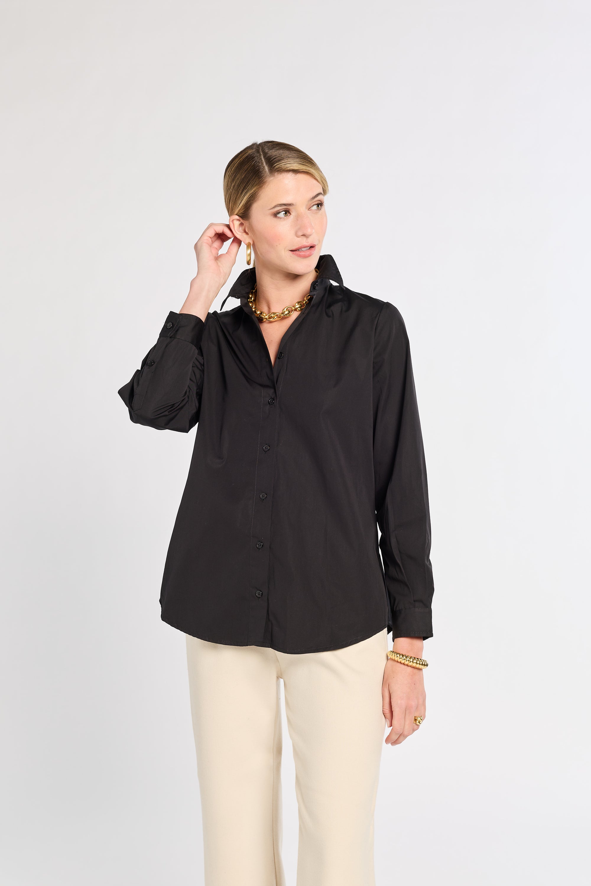 Woman wearing a black shirt and beige pants on a white background