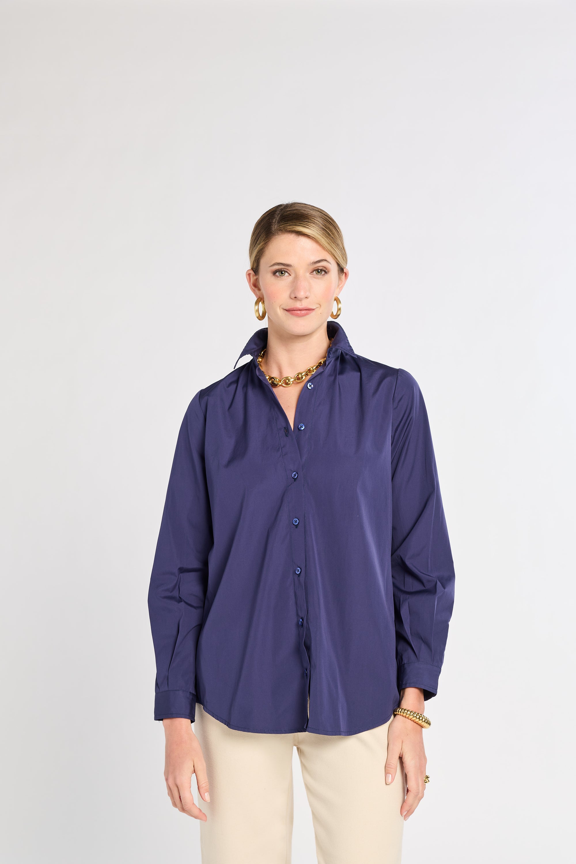 Woman wearing a navy button-up shirt on a white background