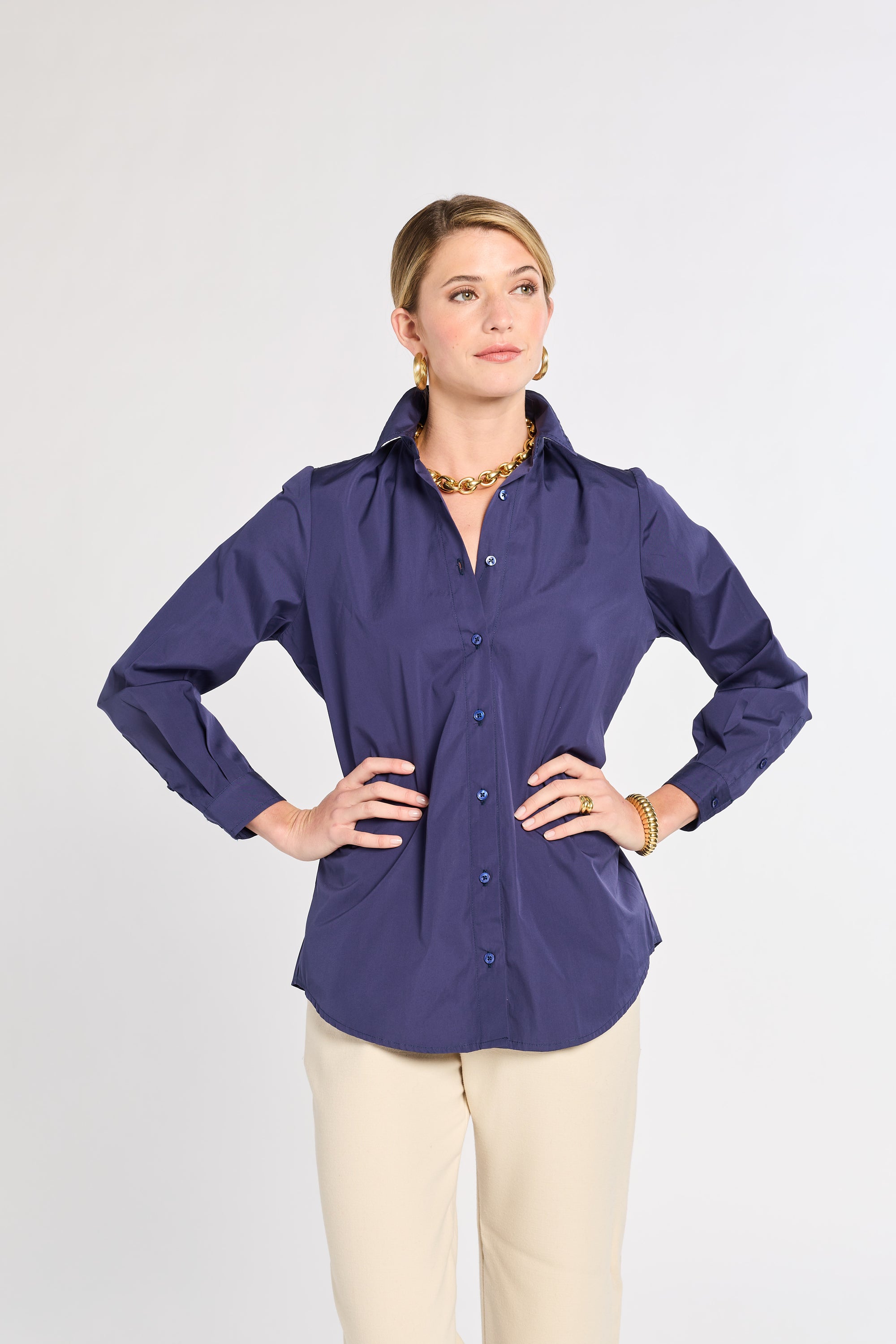 Woman wearing a navy shirt and beige pants on a white background