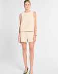 Woman wearing ivory floral shorts and top against a white background.