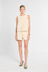 Woman wearing a light-colored sleeveless top and shorts on a white background