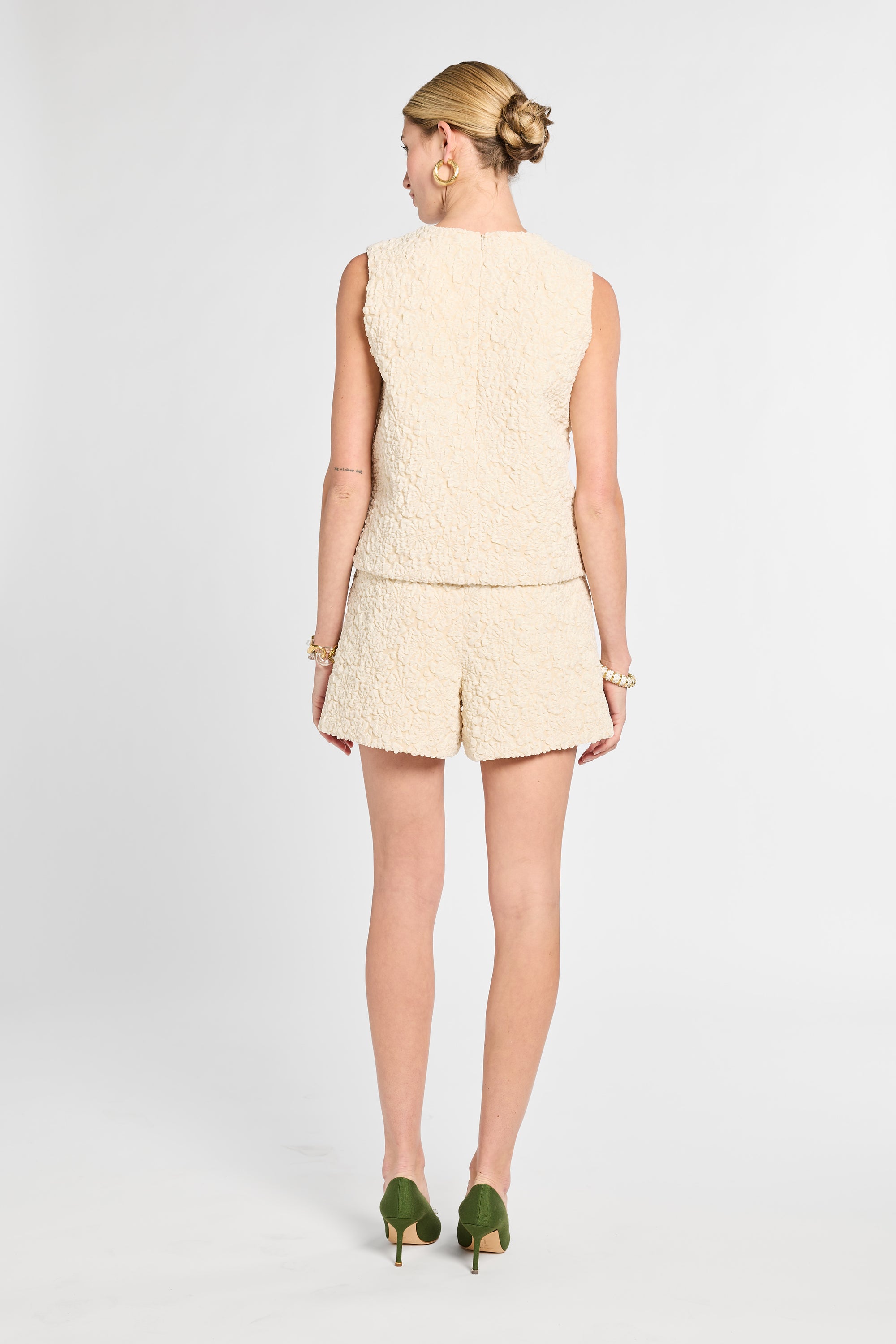 Woman wearing a beige sleeveless top and shorts set on a white background