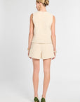 Woman wearing a beige sleeveless top and shorts set on a white background