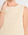 Close-up of a textured cream dress worn by a person.