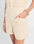 Person wearing textured cream shorts with a plain background