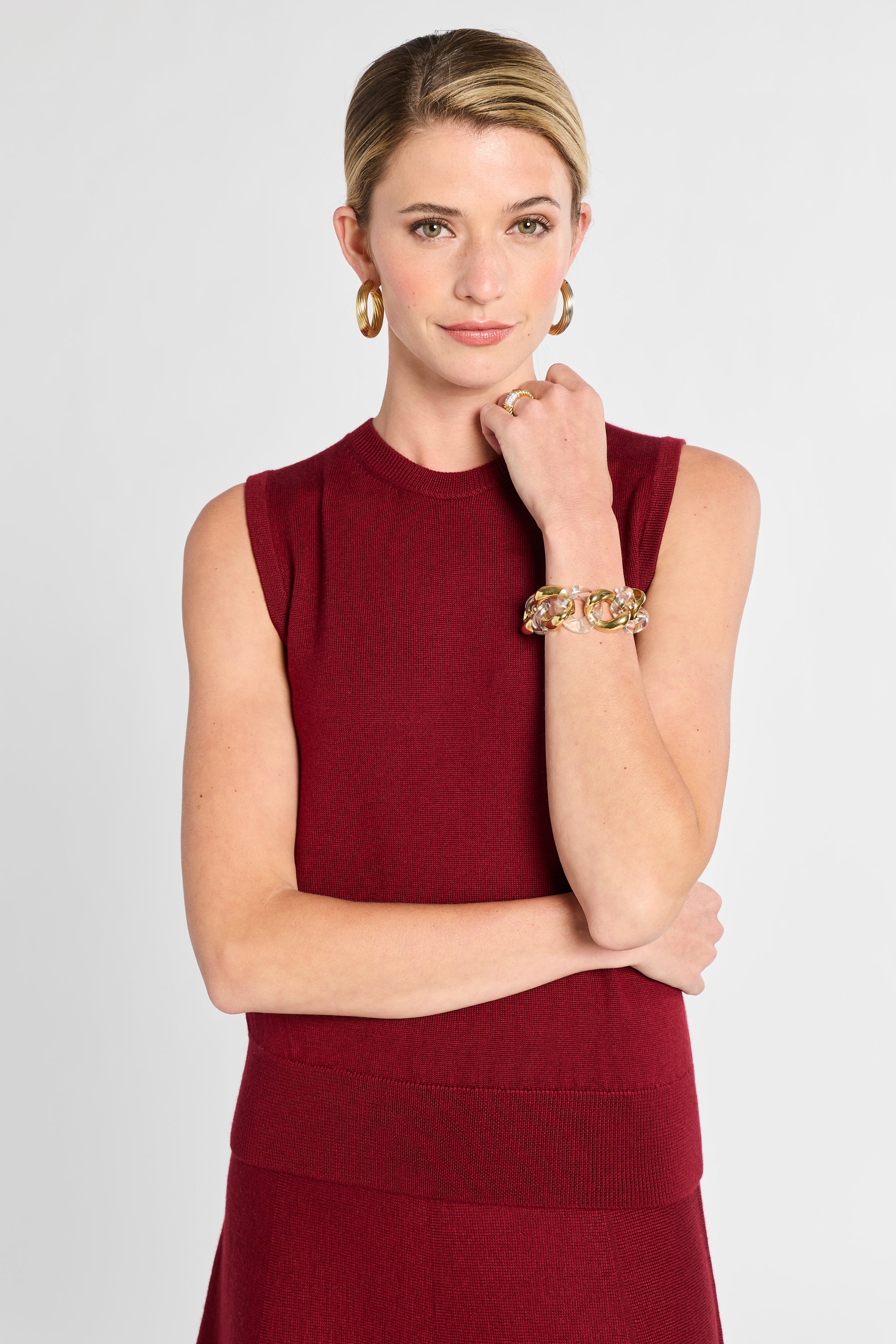 Woman wearing a red dress with gold jewelry on a light gray background
