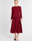 Woman wearing a burgundy sweater and skirt set on a white background