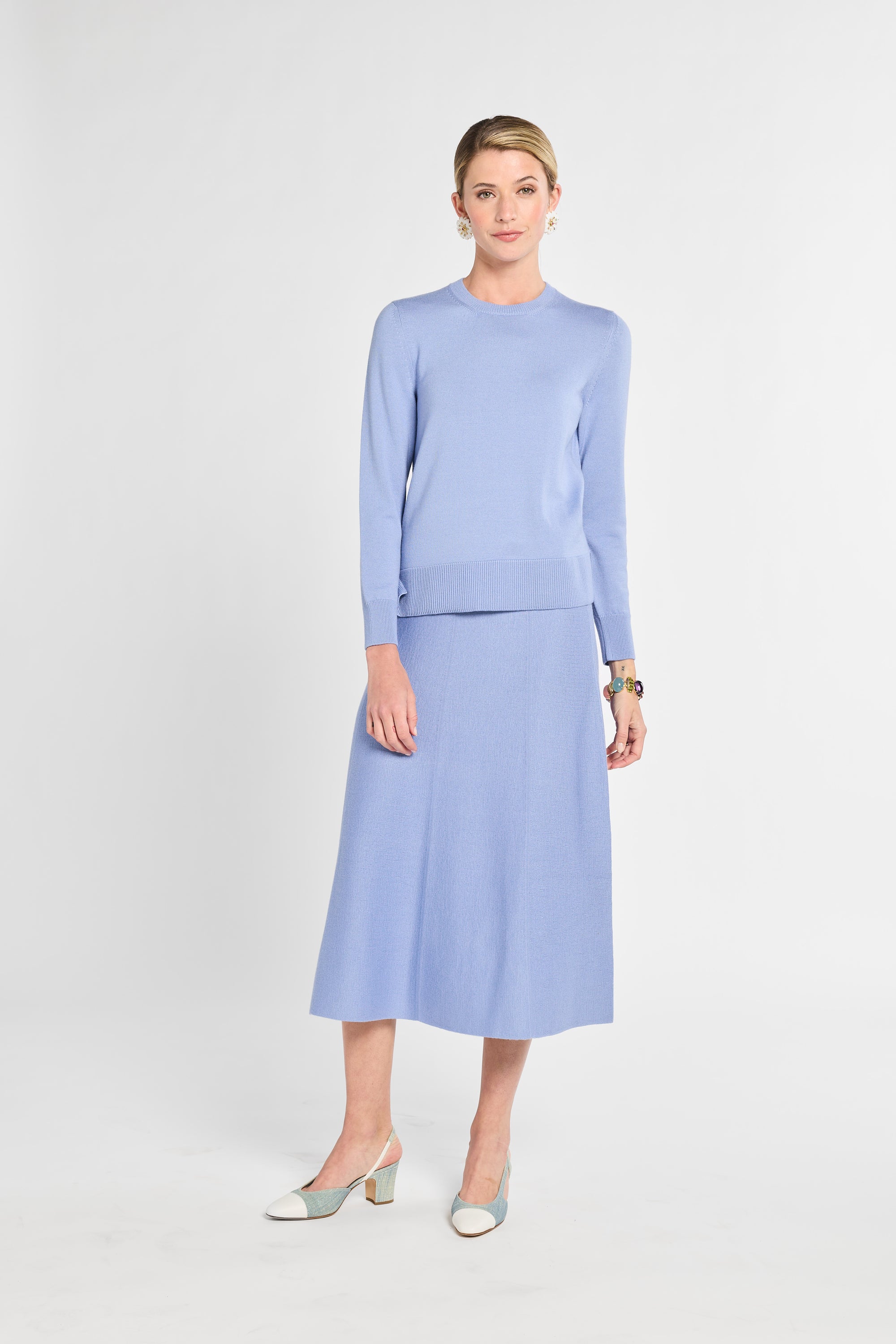 Woman wearing a light blue outfit with a top and skirt on a white background