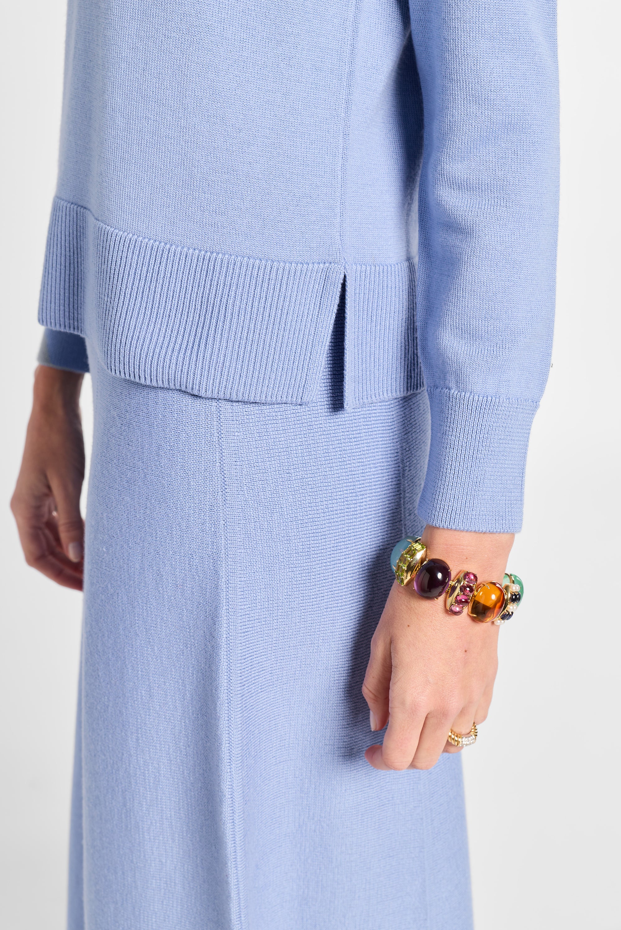 Person wearing a light blue outfit with a colorful bracelet on a white background