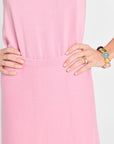 Close-up of a person wearing a pink dress with hands on hips against a white background