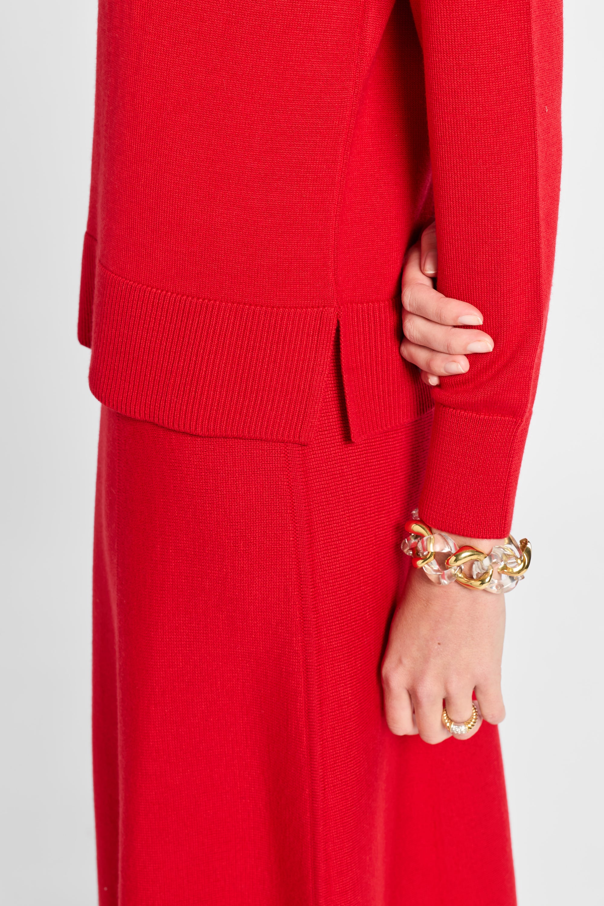 Person wearing a red outfit with a gold bracelet on a white background
