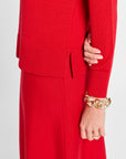 Person wearing a red outfit with a gold bracelet on a white background