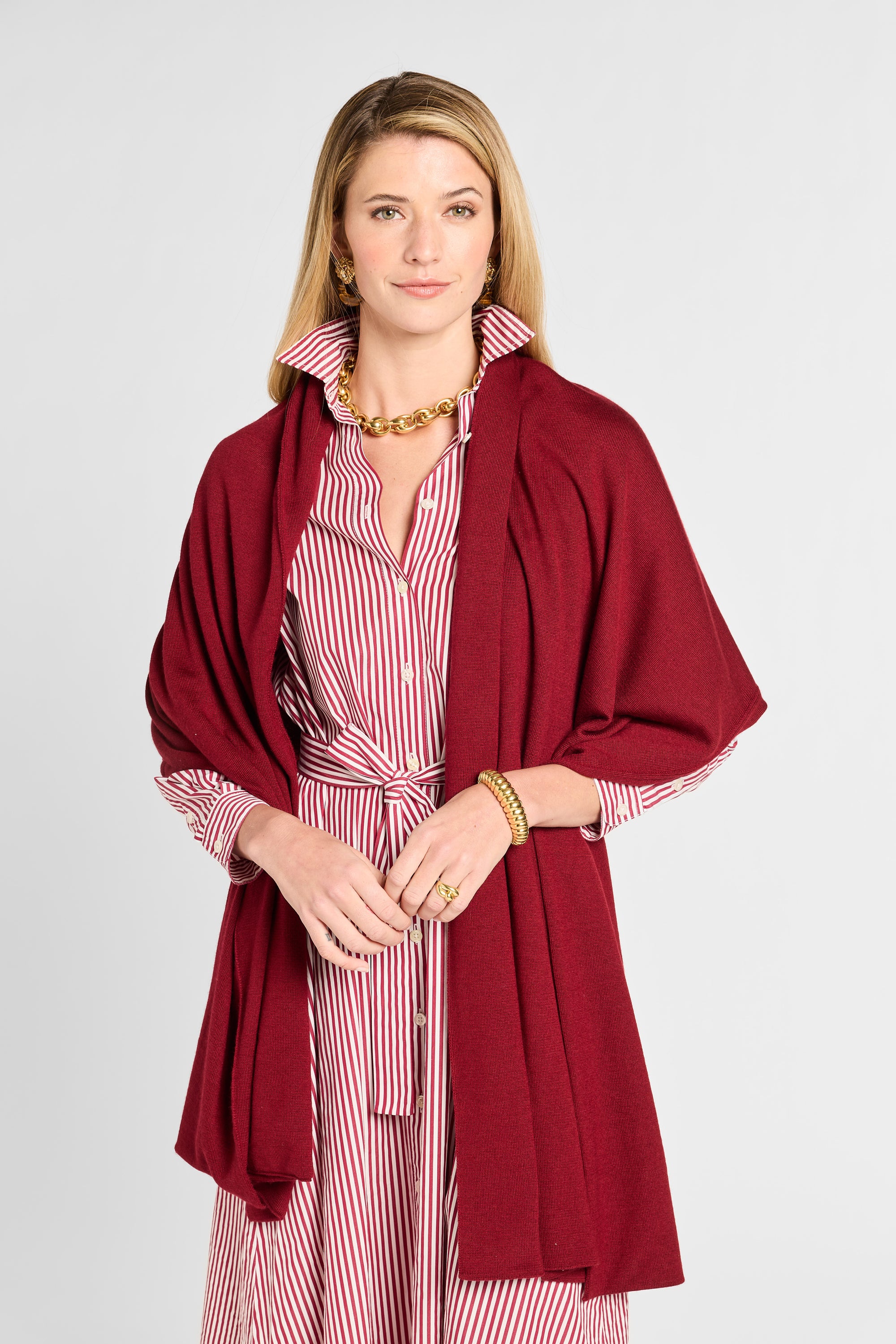 Woman wearing a red cardigan over a striped dress on a white background