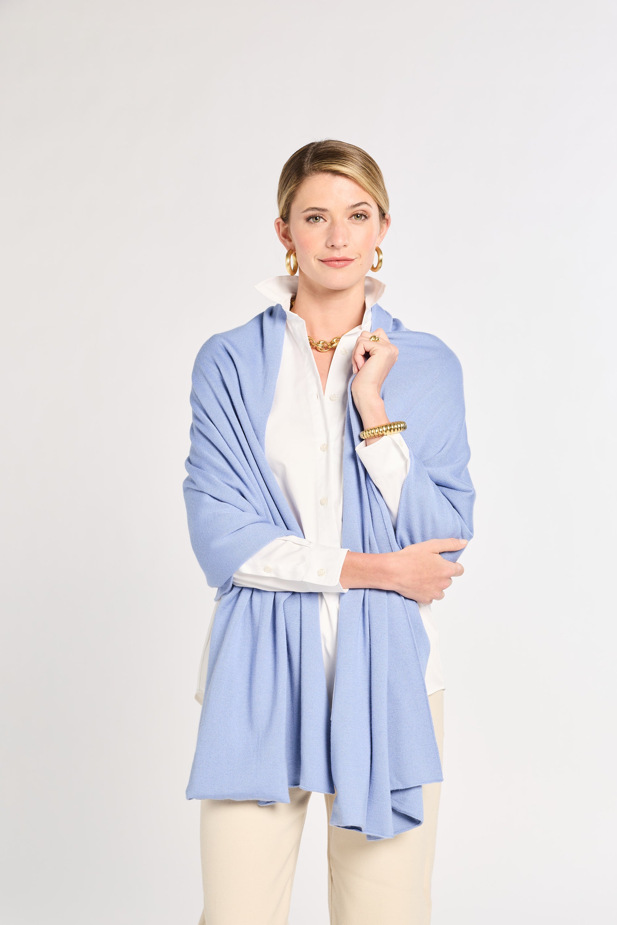 Woman wearing a light blue cardigan over a white top on a plain background