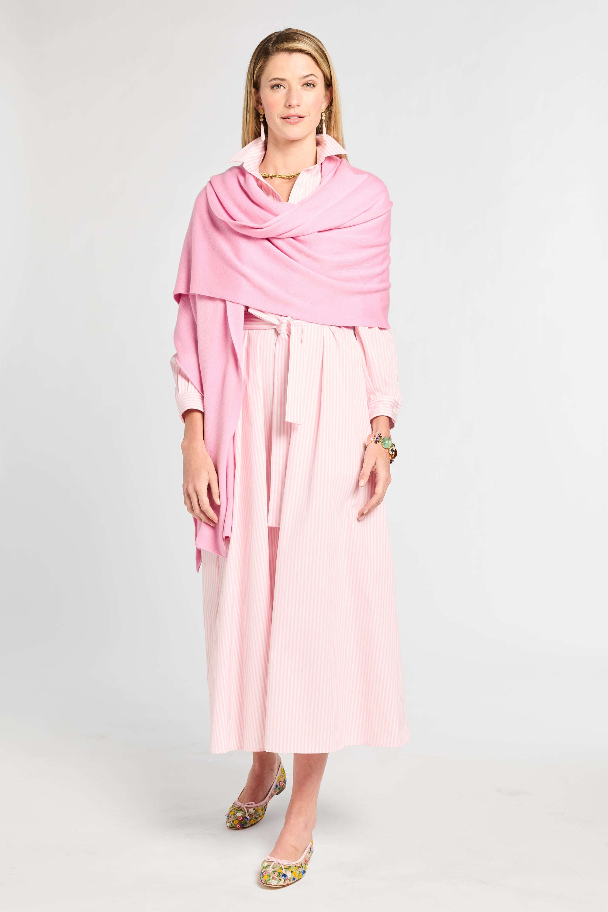 Woman wearing a pink dress and scarf on a white background
