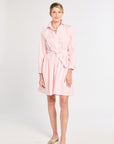 Woman wearing a pink dress with a belt on a white background
