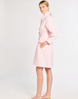 Woman wearing a light pink dress with a cutout design on a white background