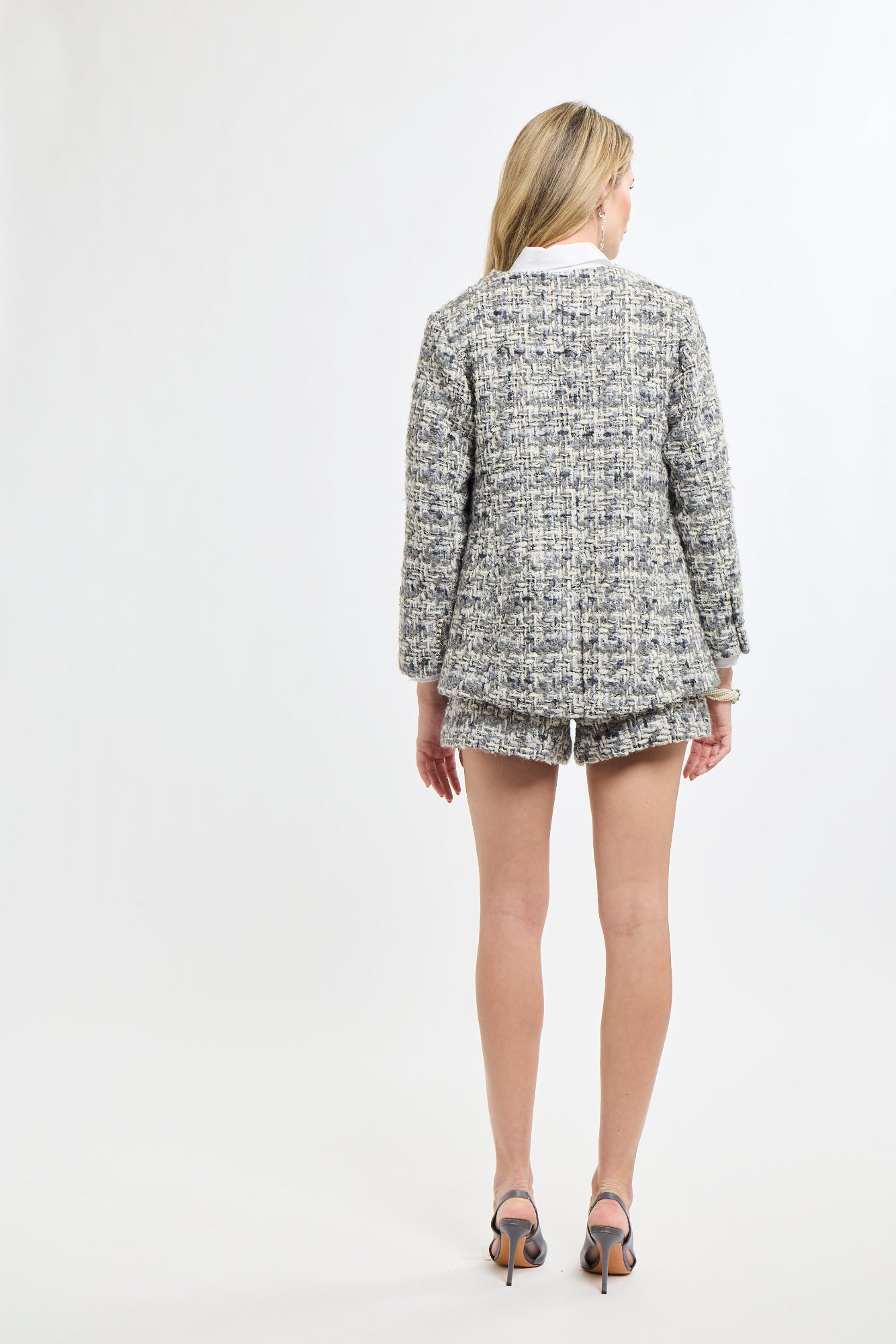 Person wearing a tweed jacket and shorts on a white background