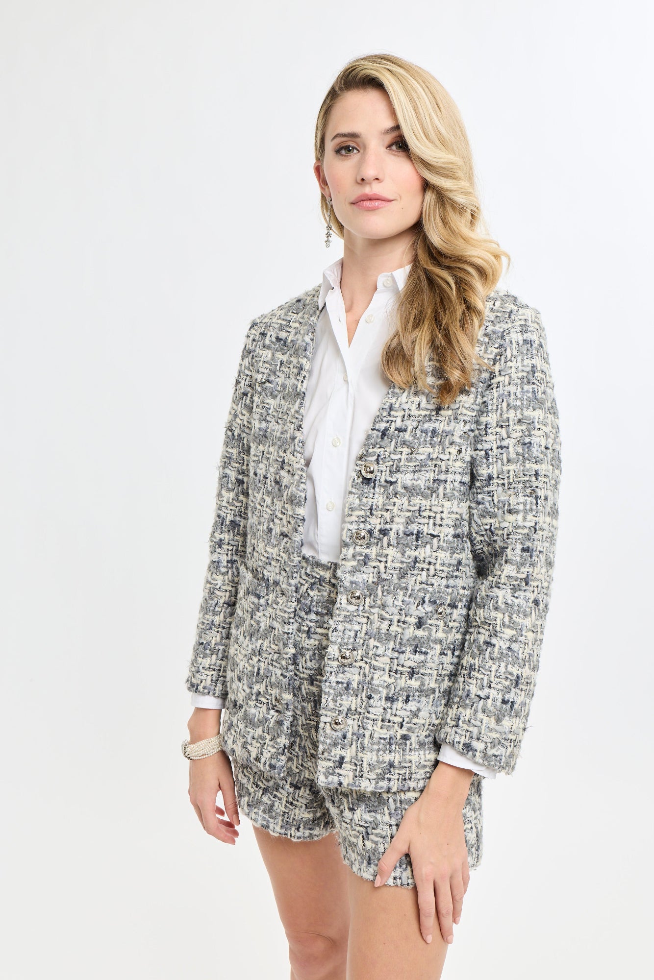 Woman wearing a tweed blazer and shorts set on a white background