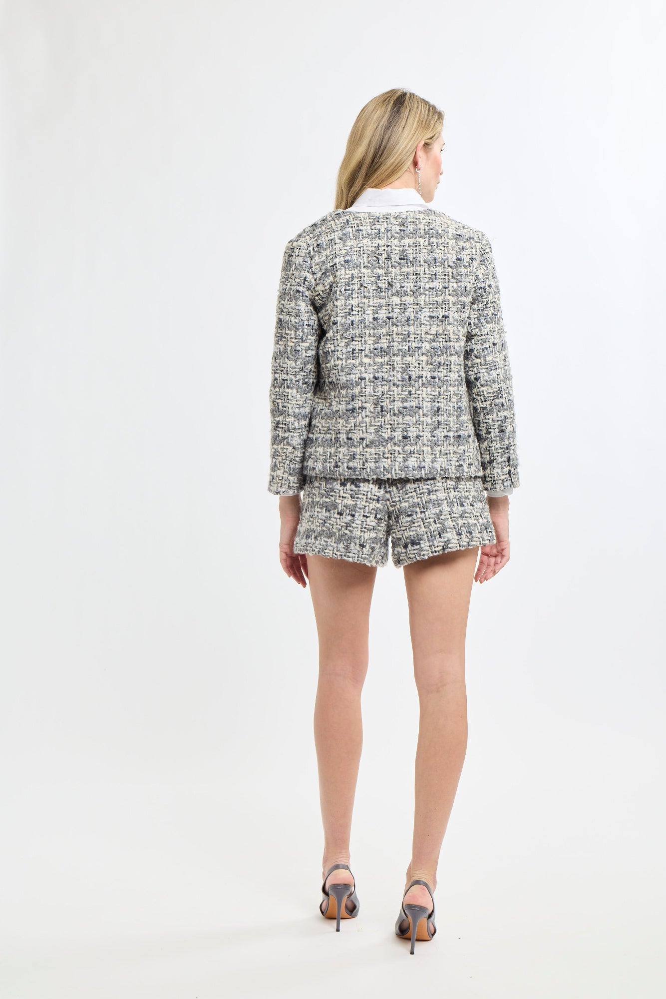 Woman wearing a tweed suit standing against a white background