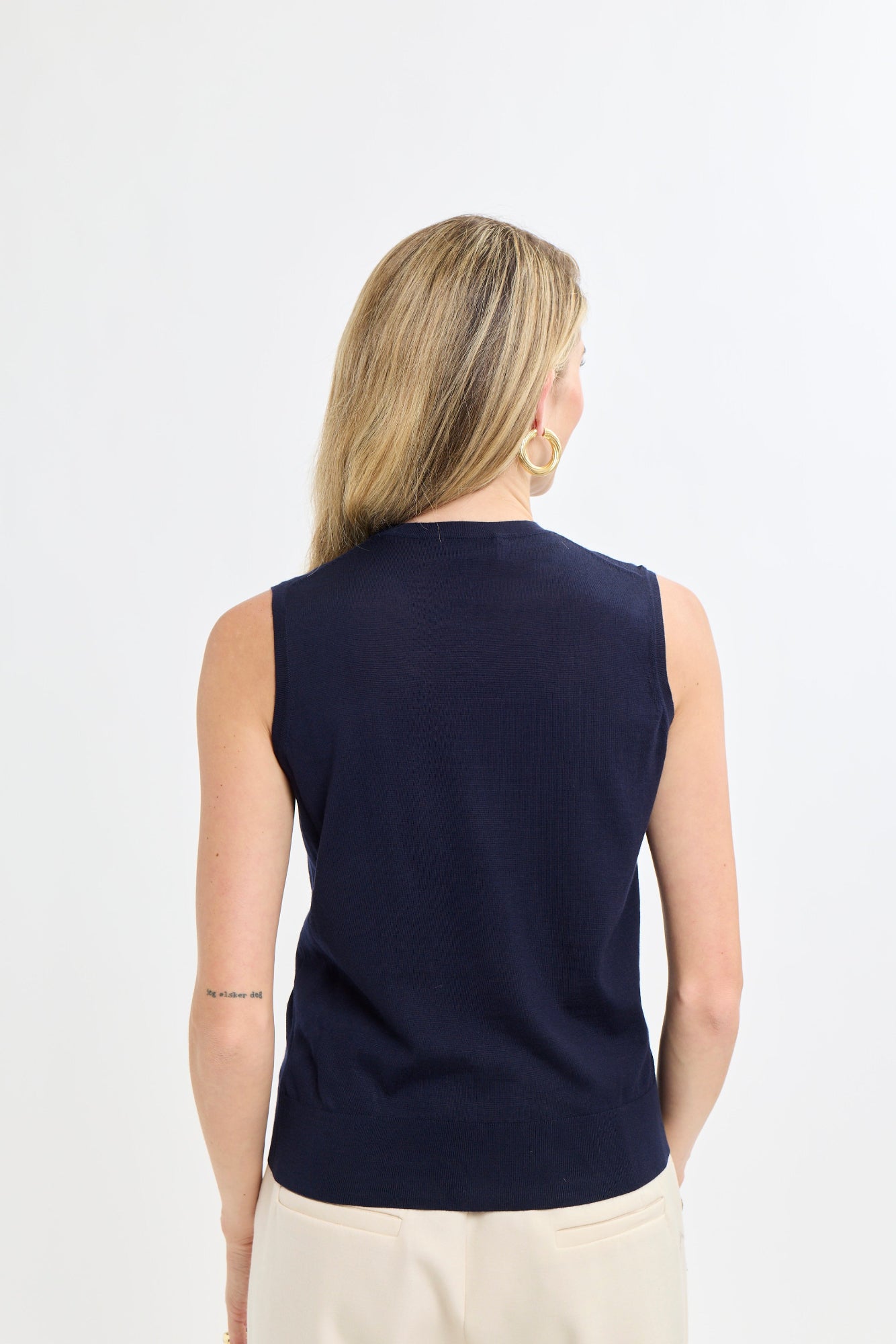 Woman wearing a navy sleeveless top on a white background