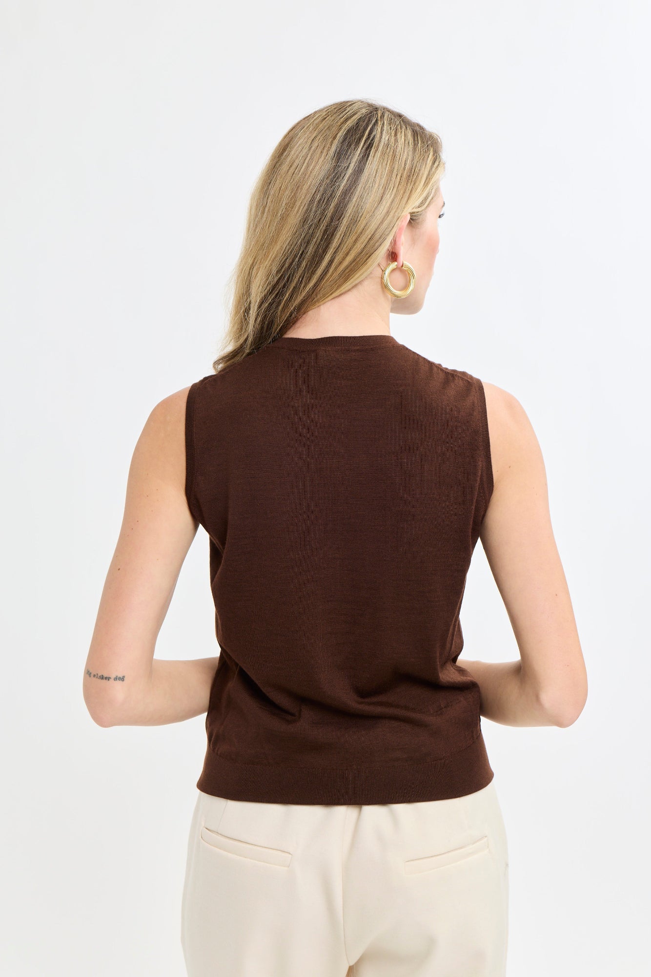 Woman wearing a brown sleeveless top against a white background