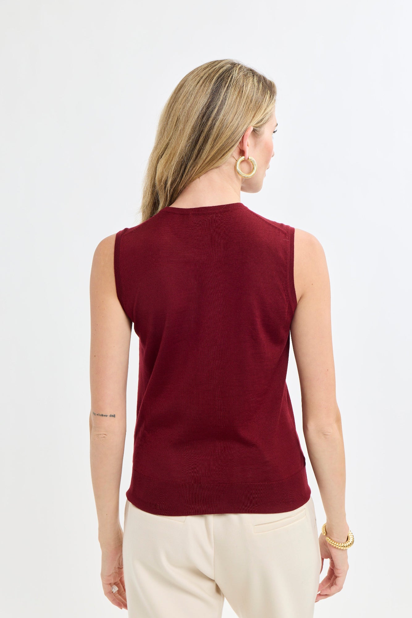Woman wearing a burgundy sleeveless top on a white background