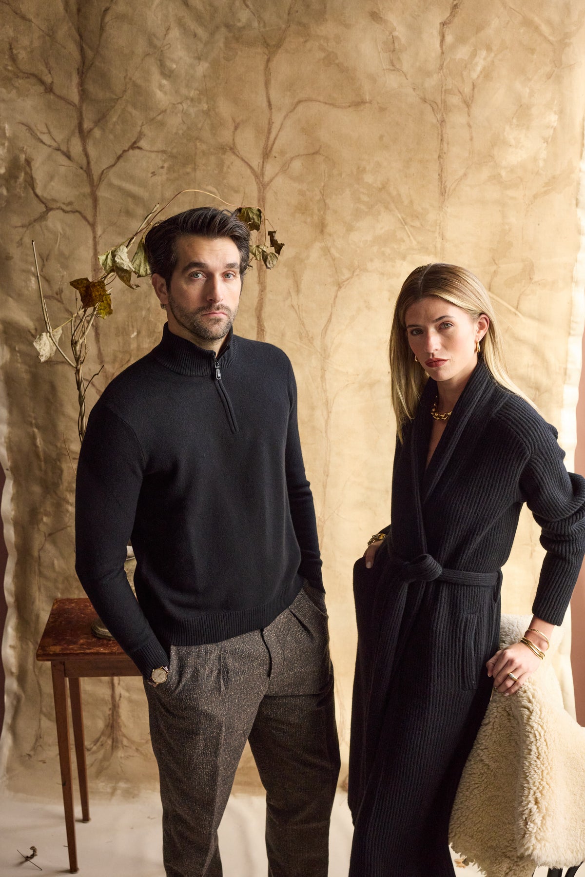 Man wearing a black cashmere quarter zip with woman next to him in a black cashmere cardigan