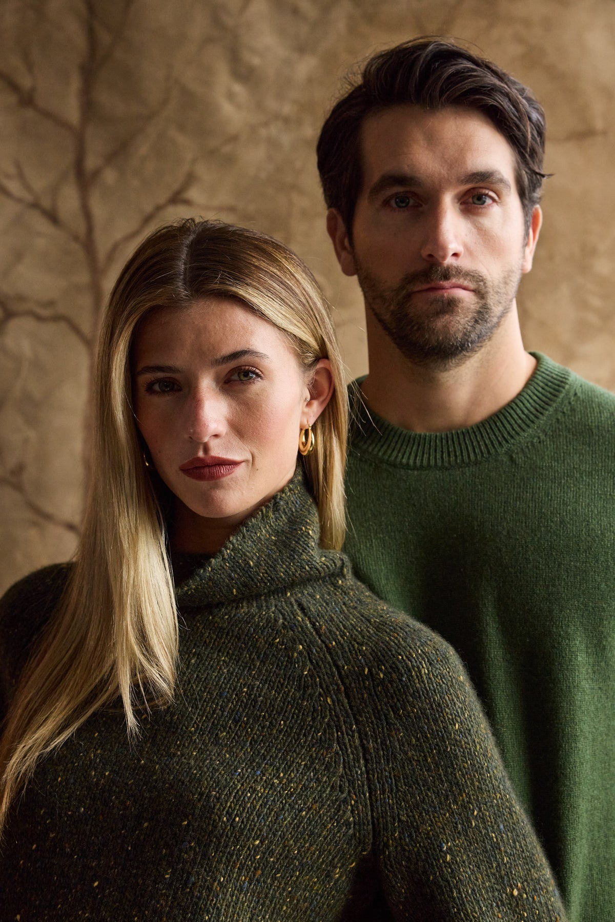 Man modeling a green cashmere crewneck with a woman beside him in a turtleneck