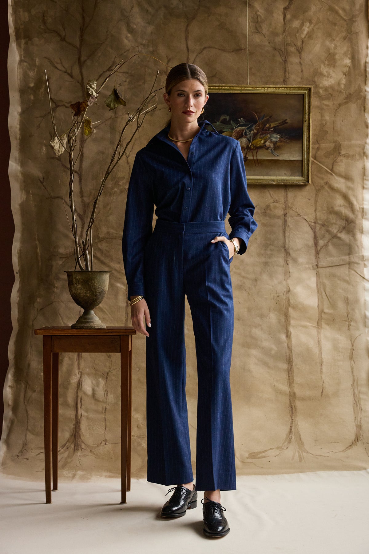 Woman modeling navy striped pants on a tan background