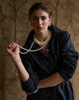 Woman modeling a stripe charcoal dress on a tan background