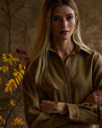 Woman modeling a green blouse with a tan background