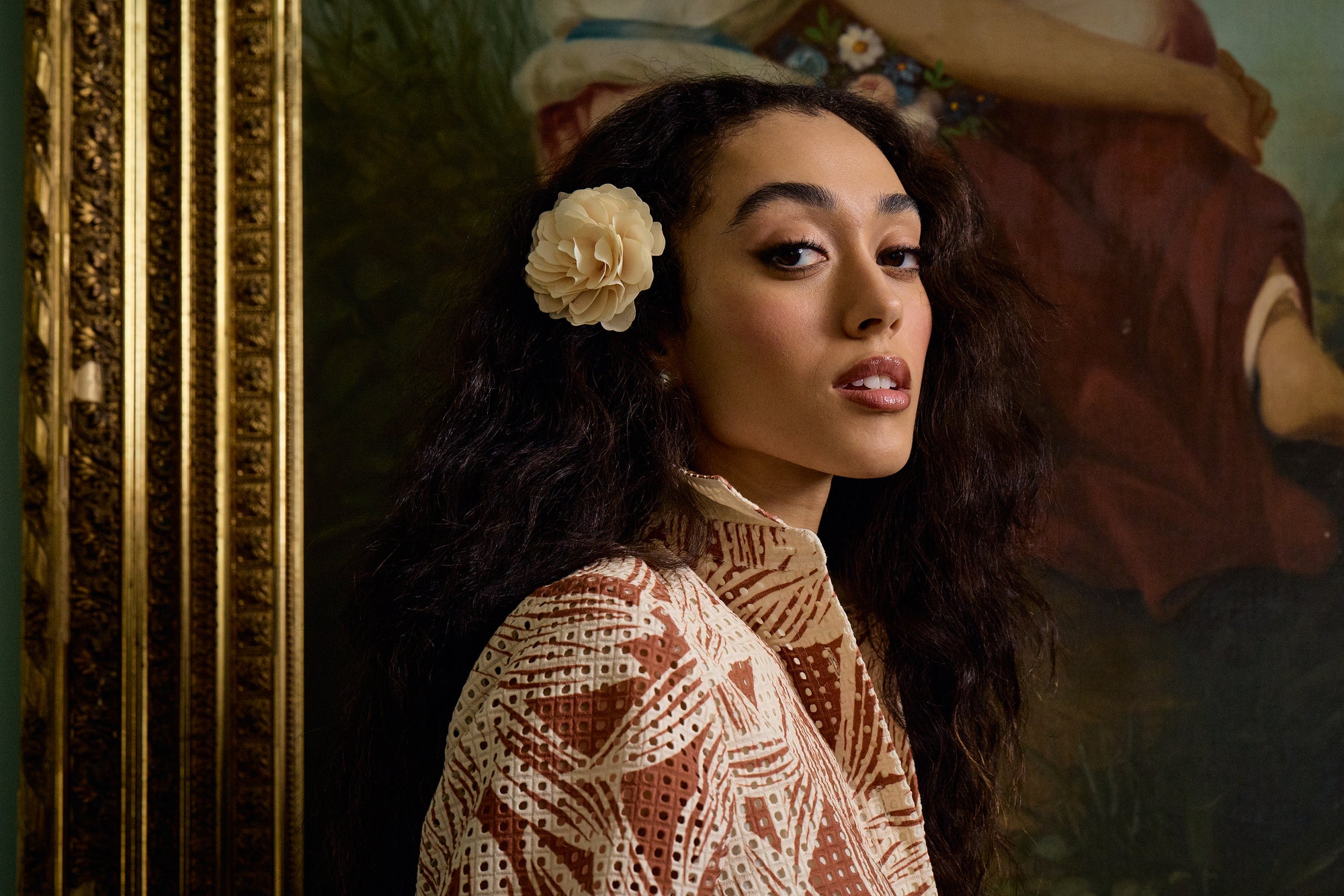 Woman with a flower in her hair against a decorative wall