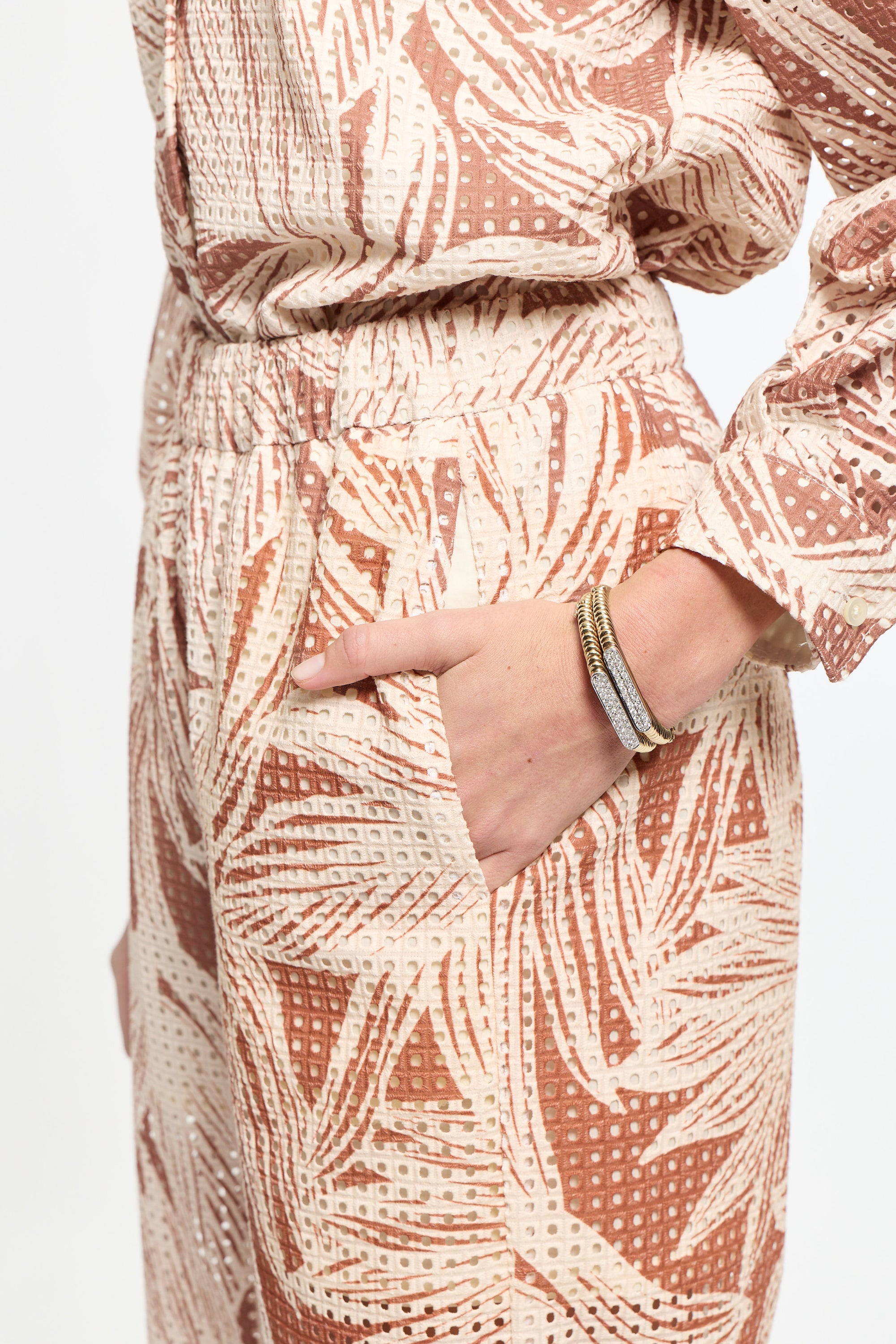 Person wearing a patterned outfit with a hand pointing to the fabric.