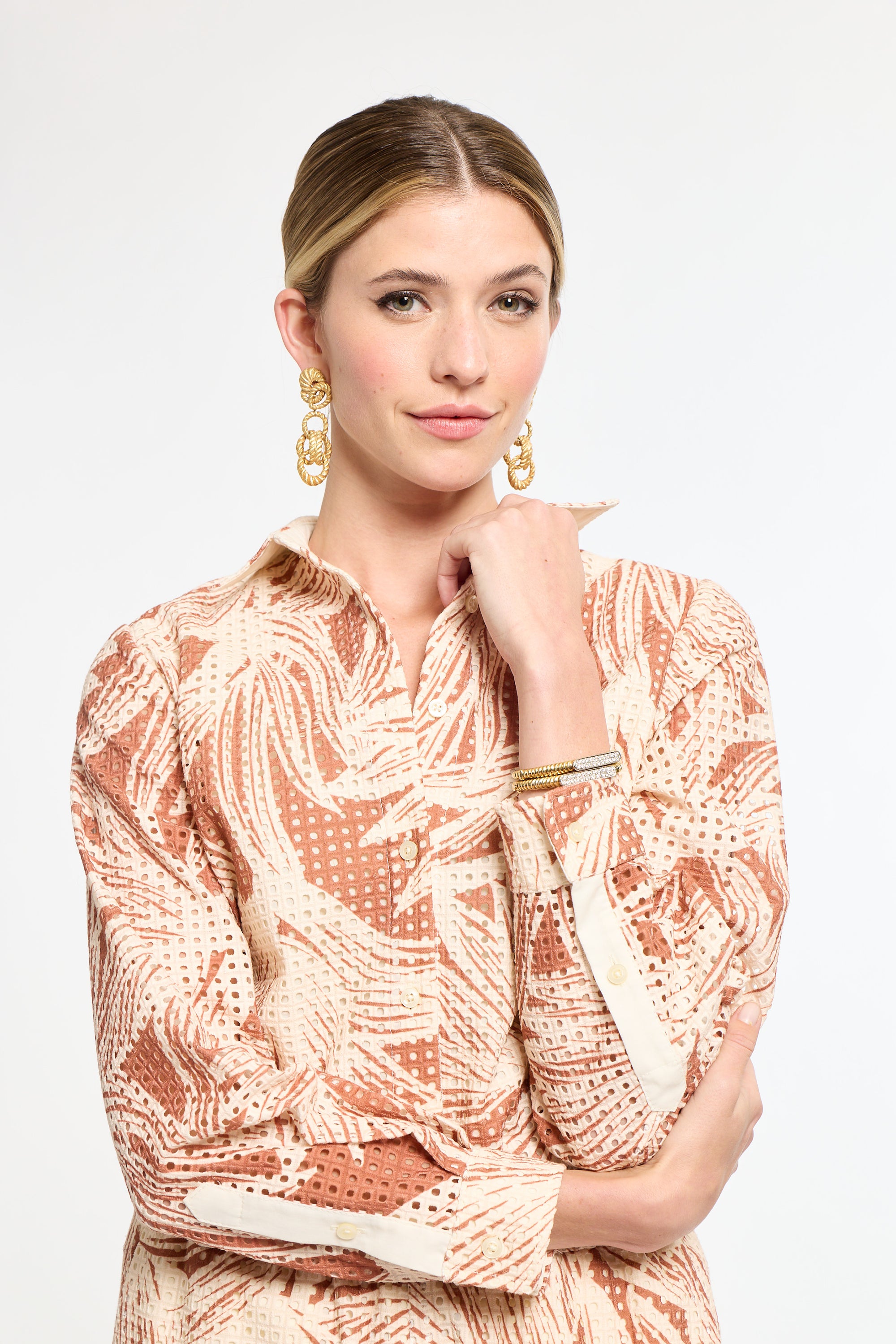 Woman wearing a patterned dress with gold earrings on a white background