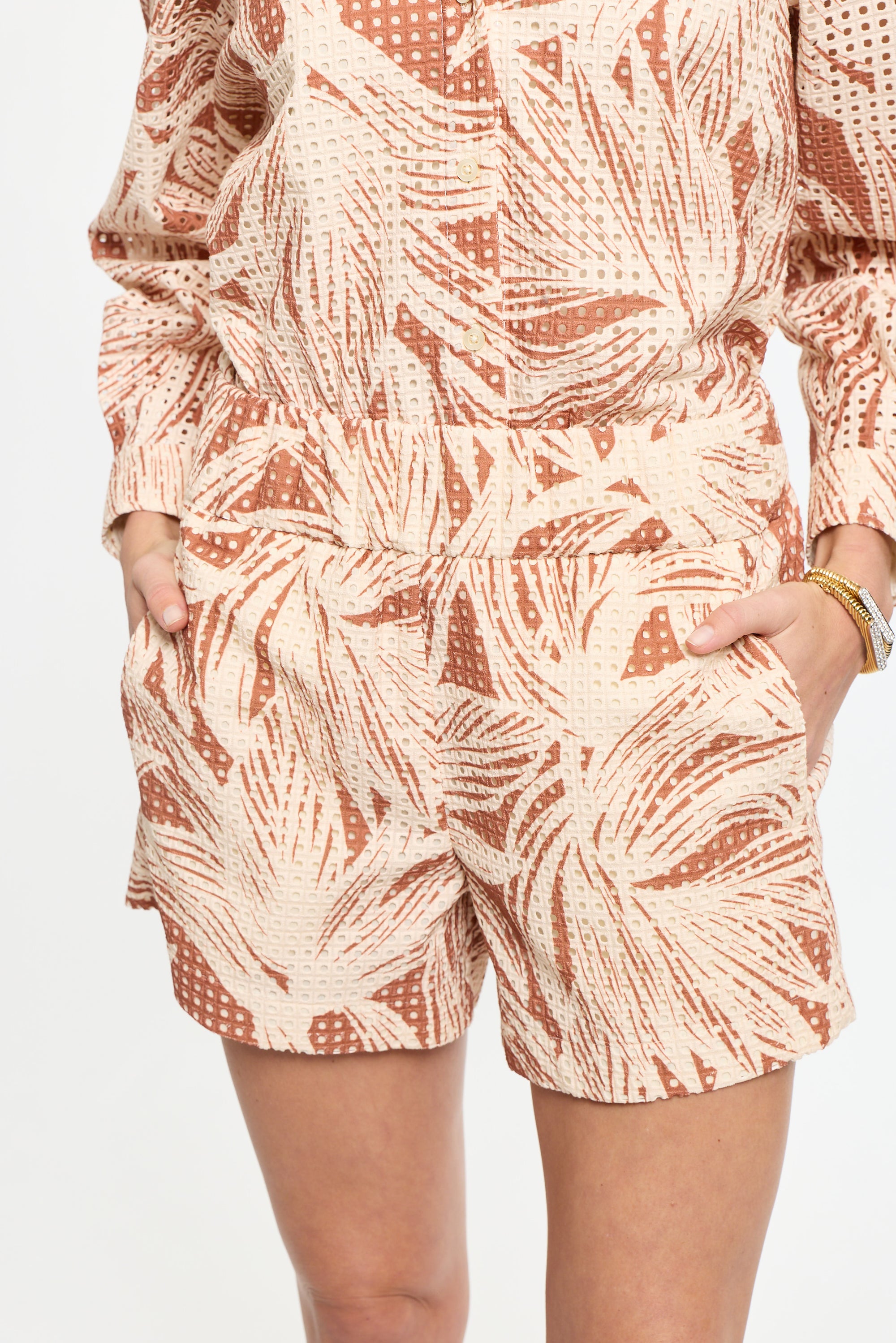 Person wearing a patterned outfit with shorts and a top on a plain background