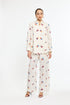Woman wearing a cream-colored outfit with colorful floral patterns on a white background