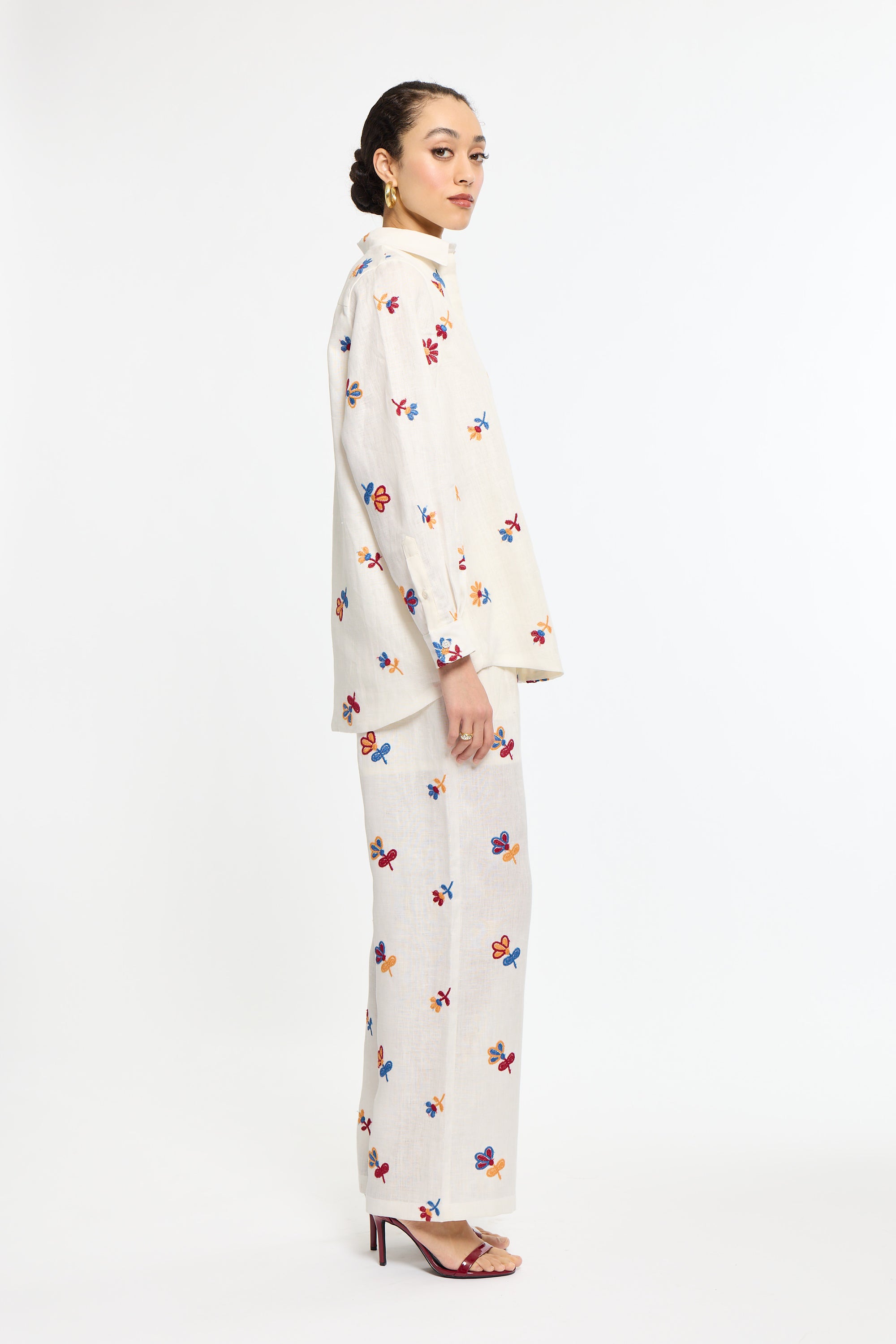 Woman wearing a white outfit with colorful patterns on a white background