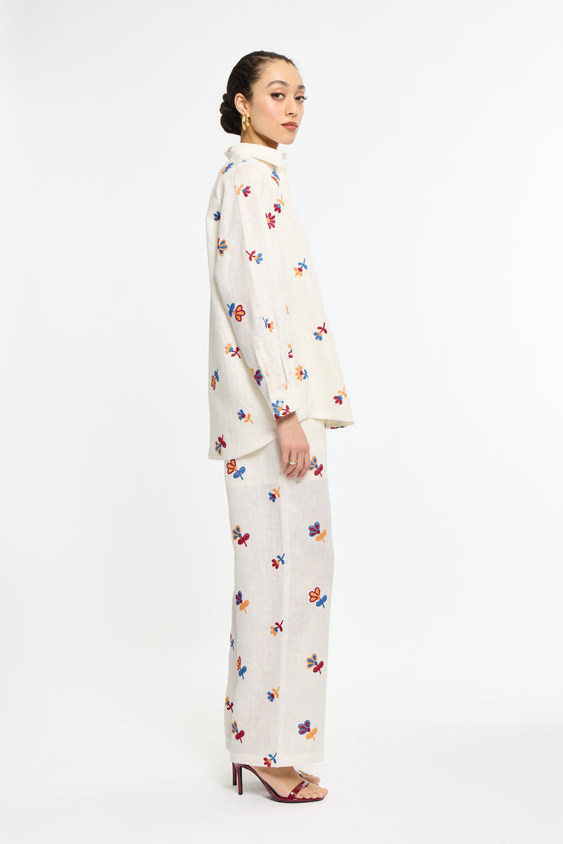 Woman wearing a white outfit with colorful patterns on a white background