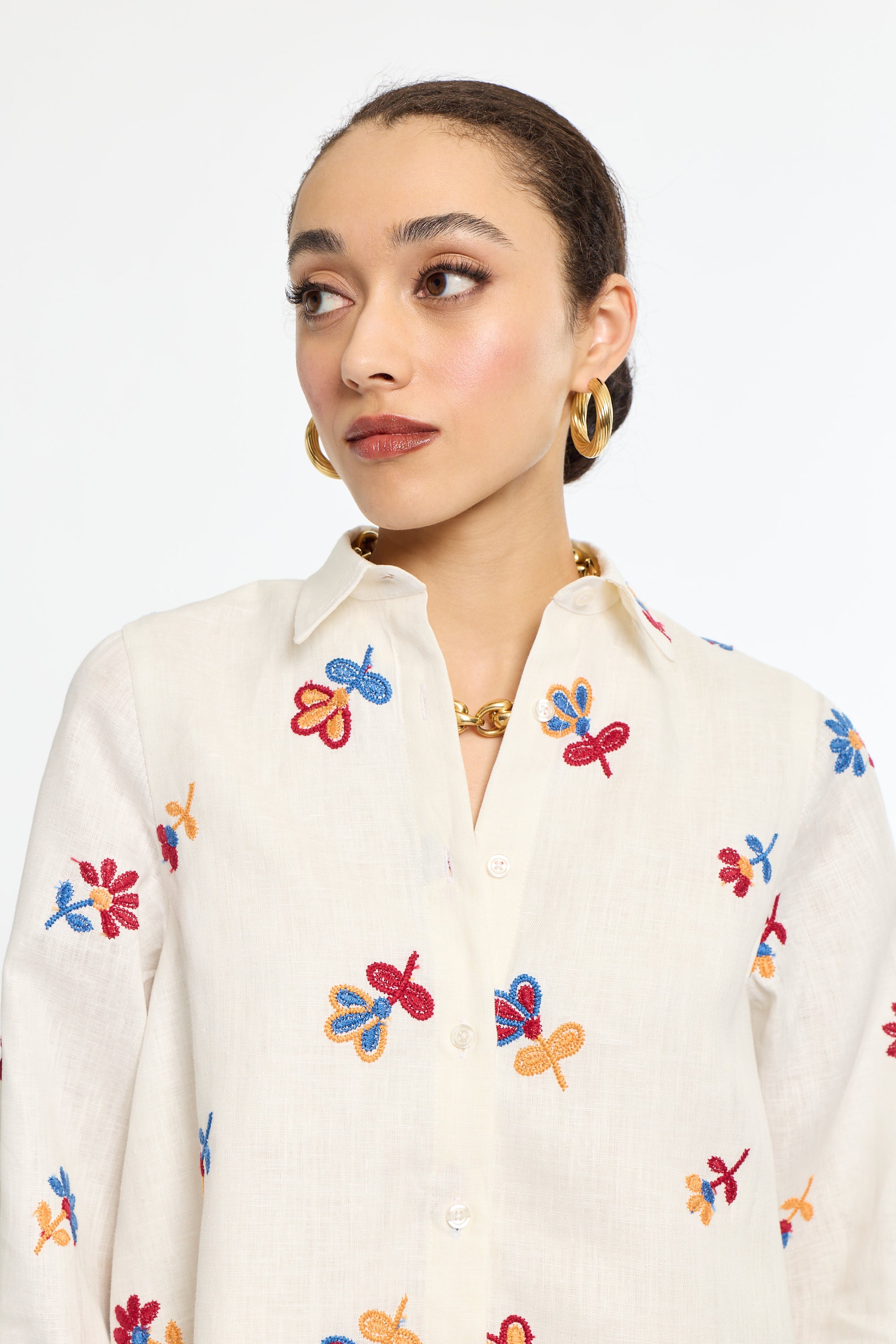 Woman wearing a cream-colored shirt with colorful butterfly patterns on a white background
