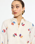 Woman wearing a cream-colored shirt with colorful butterfly patterns on a white background