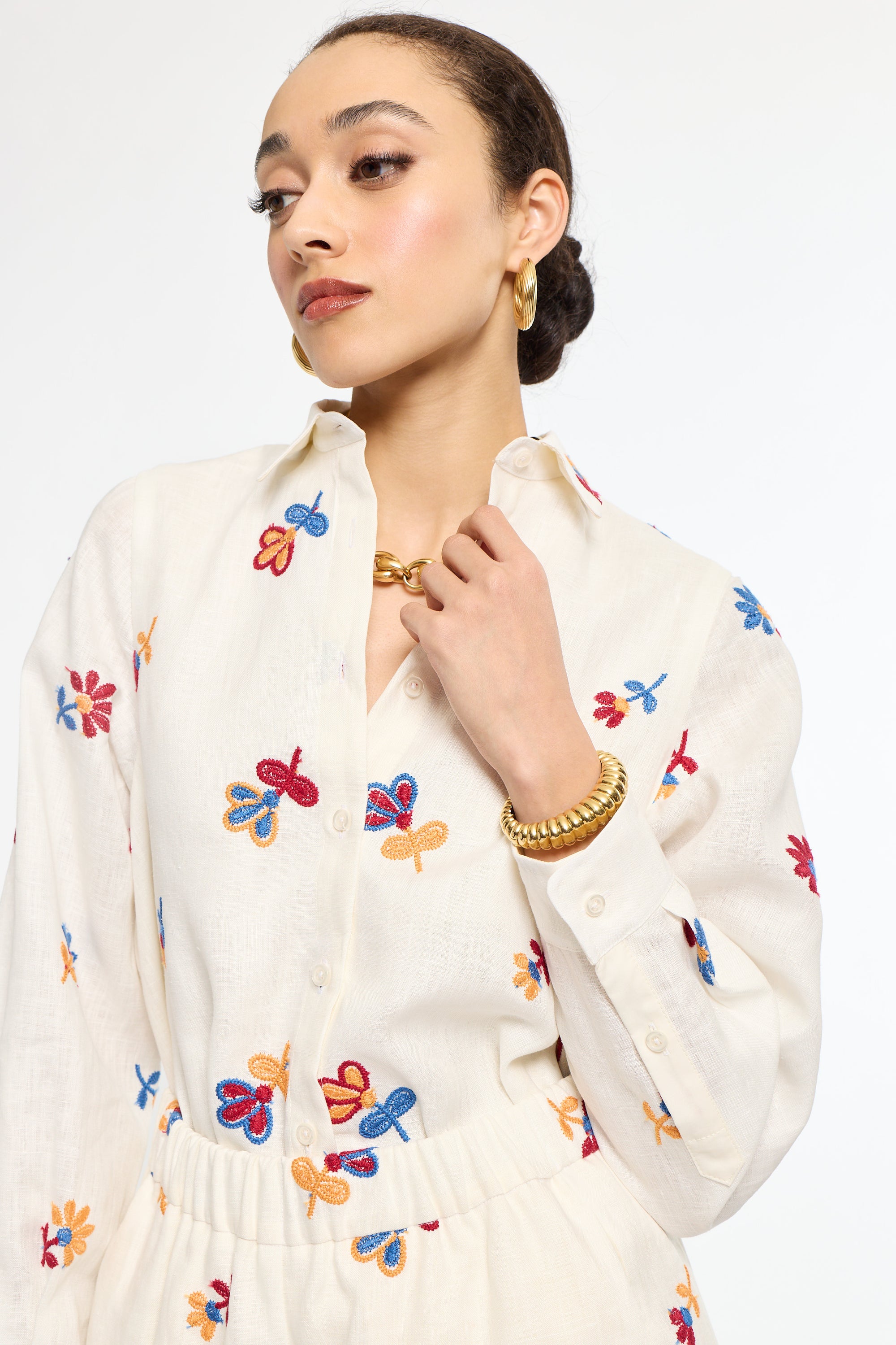 Woman wearing a white blouse with colorful butterfly patterns on a plain background
